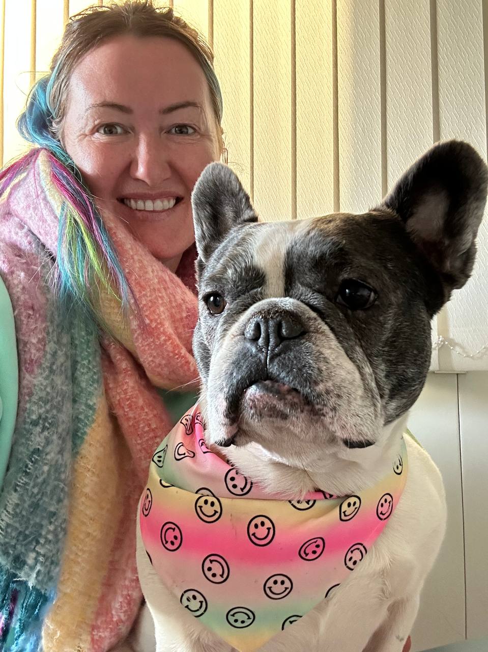 Viviana smiling beside a French bulldog in a rainbow bandana
